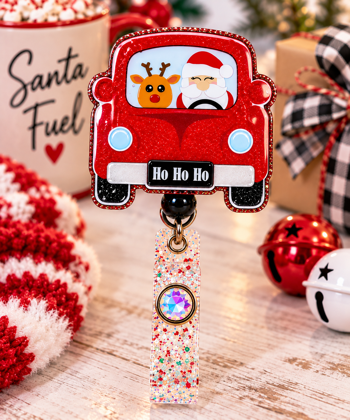 Ho Ho Ho red car badge reel with black bead and gem-accented strap beside holiday props