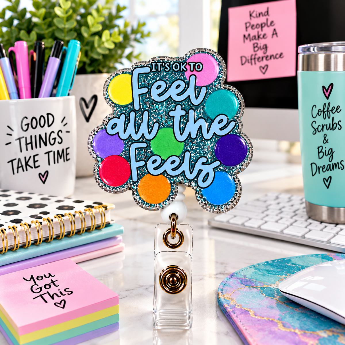 Teal glitter Feel All the Feels badge reel displayed on a colorful office desk