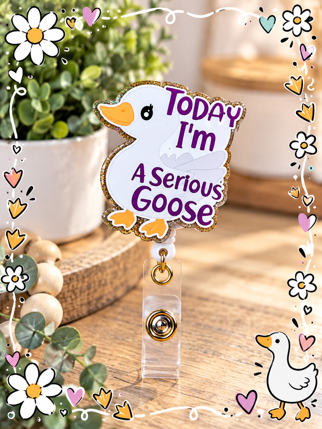 White goose badge reel displayed beside a pink tumbler and floral notebook