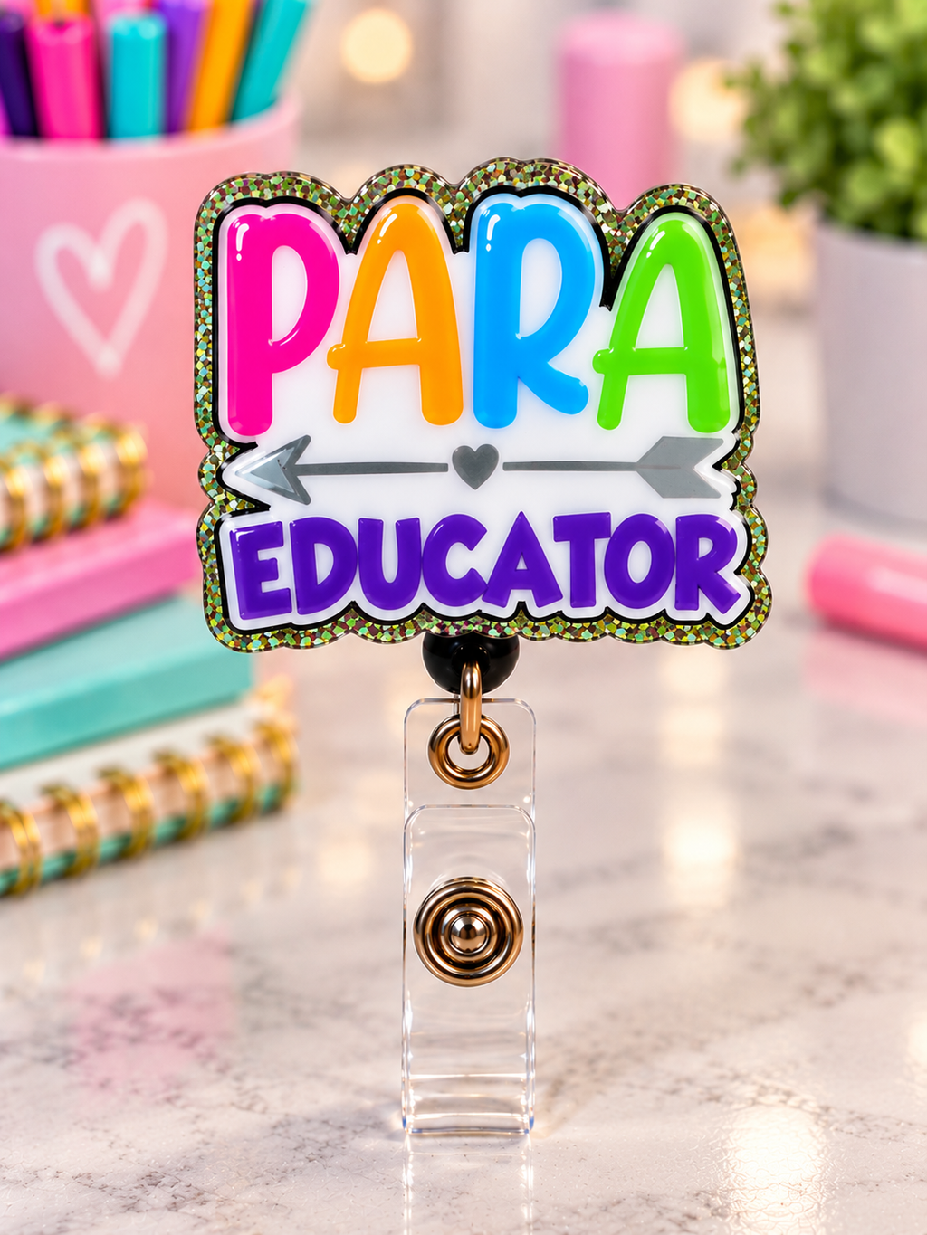 Colorful Para Educator badge reel with purple lettering, heart-and-arrow motif, and glitter edging