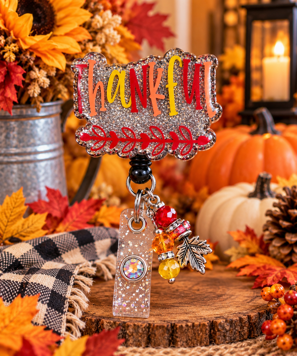 Thankful badge reel with glitter strap and gem-accented snap beside fall decorations