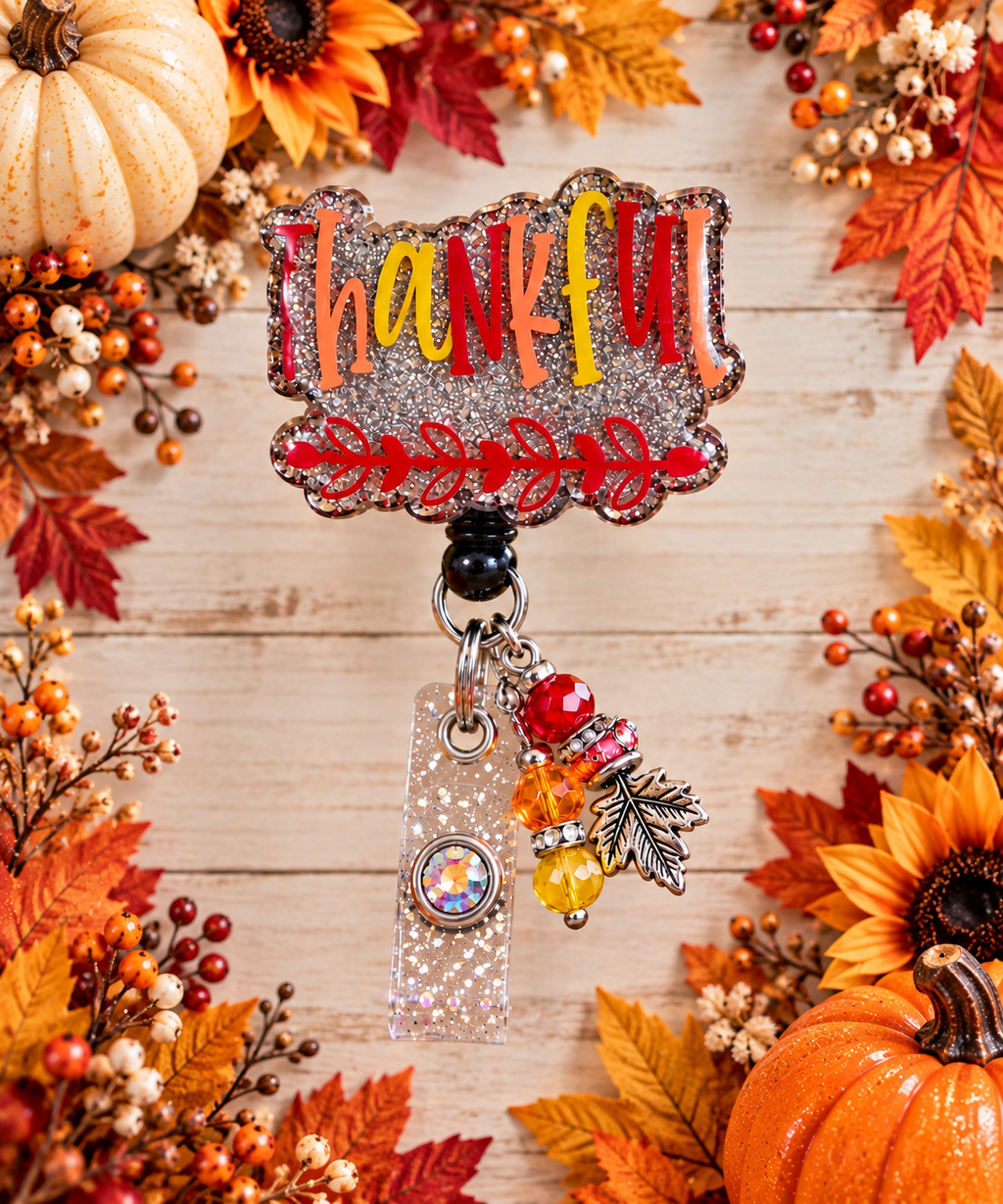 Thankful fall badge reel with red orange and yellow beads displayed beside pumpkins